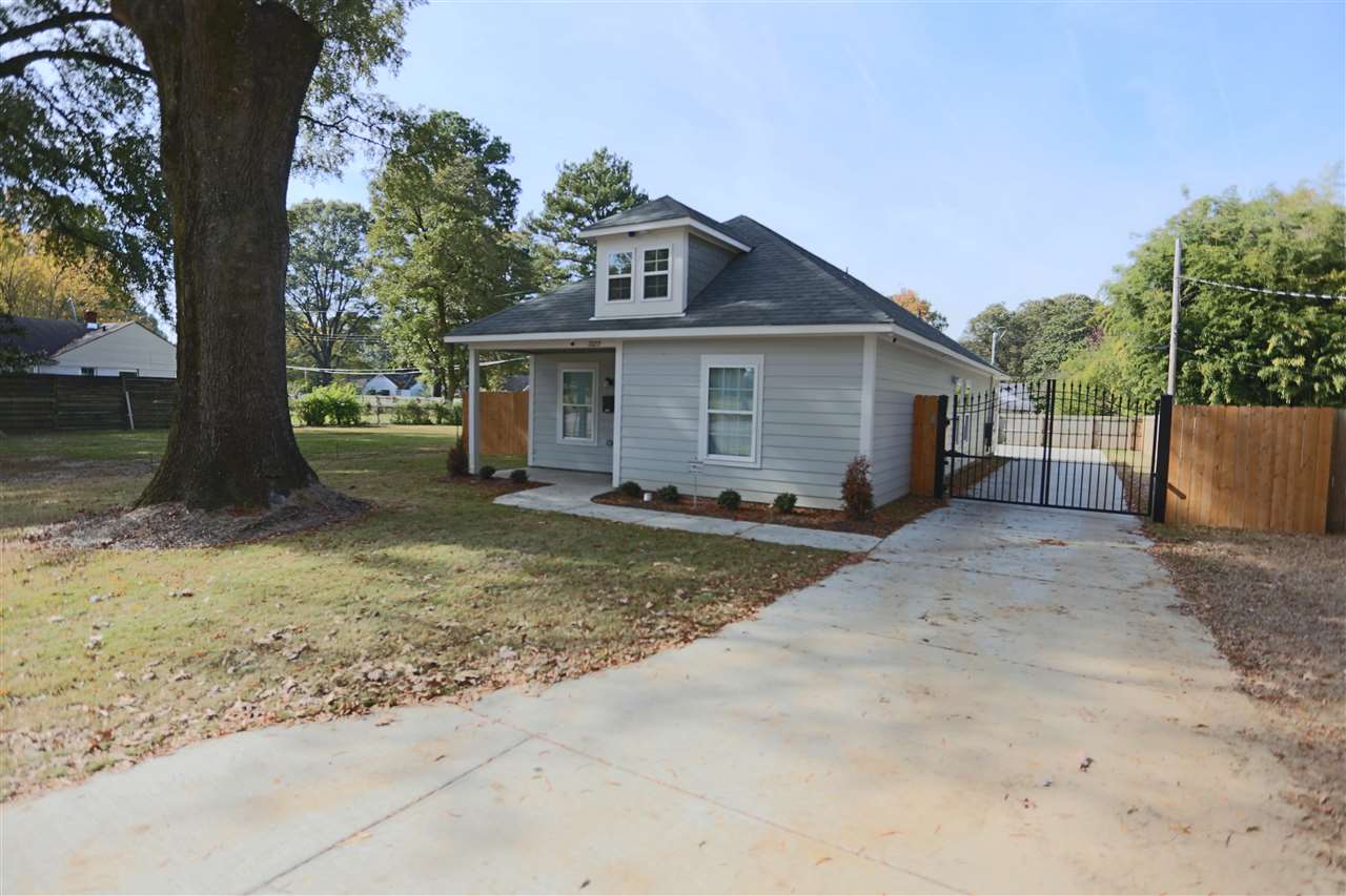 a view of a house with a yard and large tree