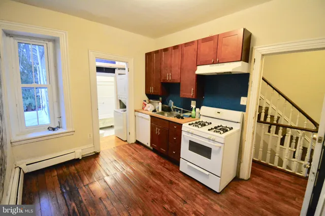 a kitchen with a stove a sink and a wooden floor