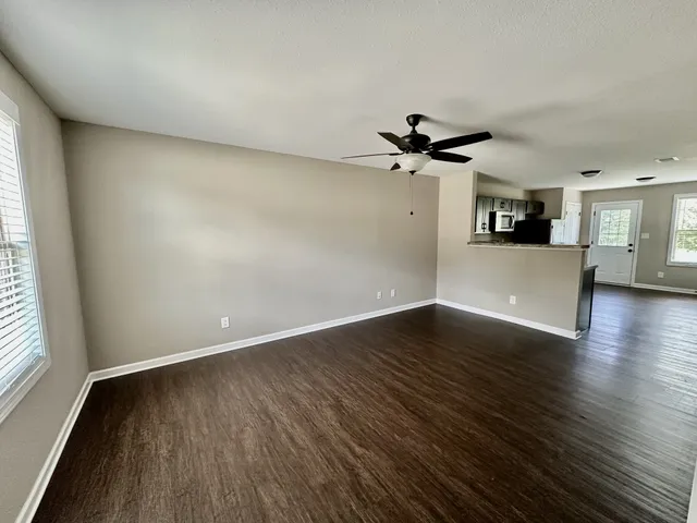 an empty room with wooden floor and a ceiling fan