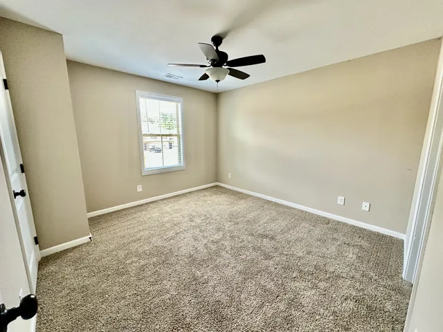 an empty room with a ceiling fan and window
