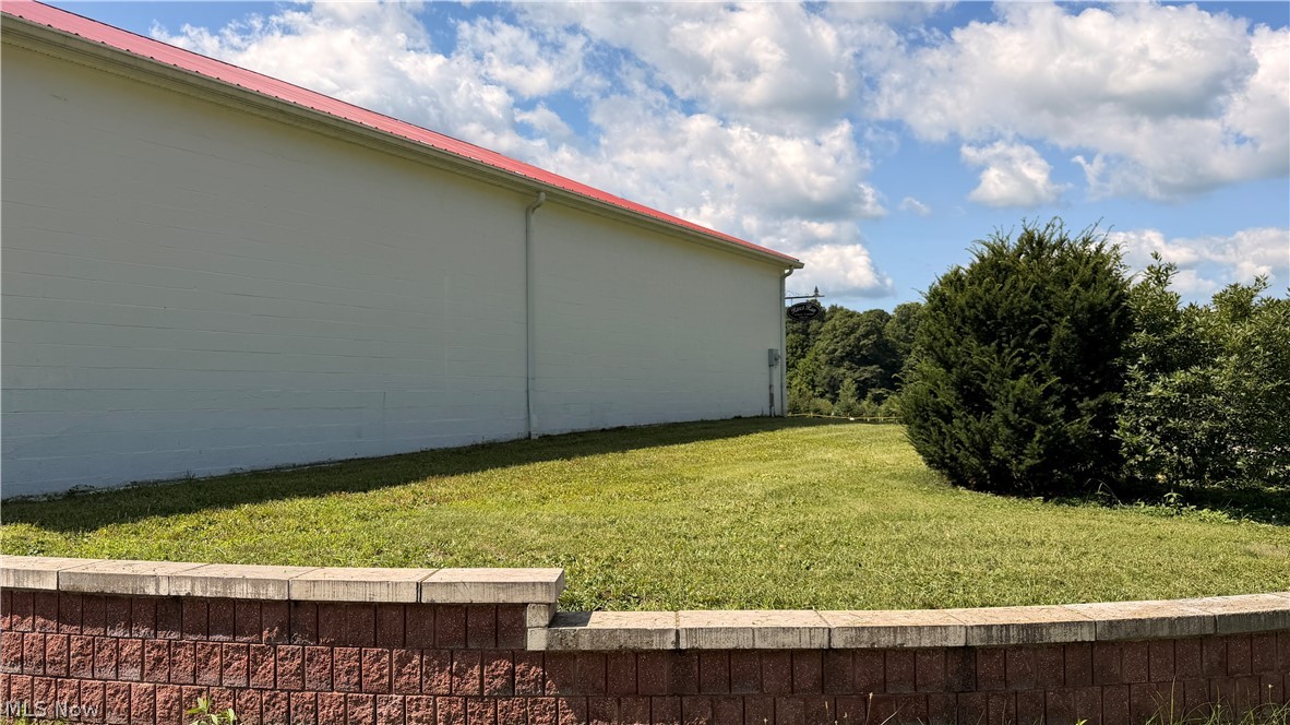 5620 Streeter Road Mantua, OH 44255 - Photo 21 of 45 White exterior structure with a red roof, bordered by a textured block retaining wall and a manicured lawn