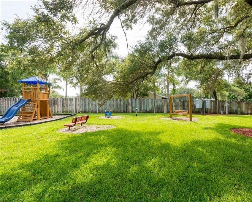 2375 Fox Chase Boulevard, Unit 260 Palm Harbor, FL 34683 - Photo 37 of 38 a view of a swimming pool with a bench and trees