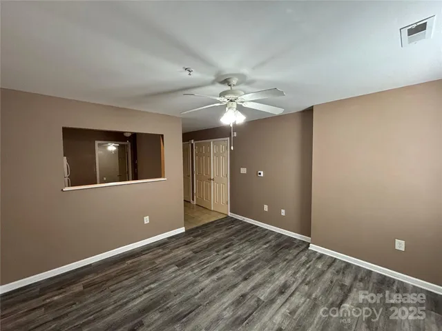 a view of an empty room with window and wooden floor