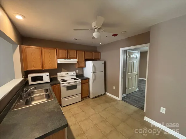 a kitchen with a refrigerator a stove top oven a sink and cabinets
