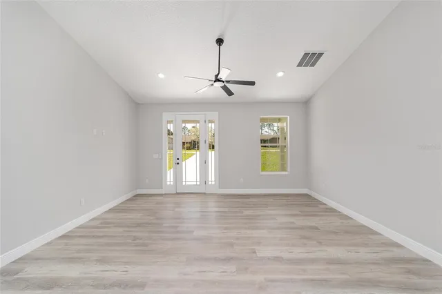 a view of an empty room with window and wooden floor