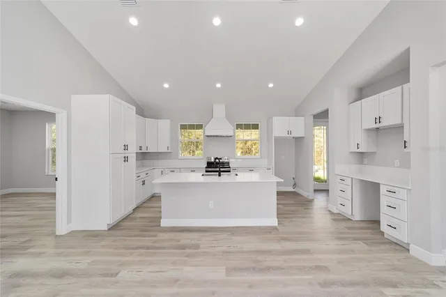 a view of a kitchen with kitchen island a sink wooden floor and a refrigerator