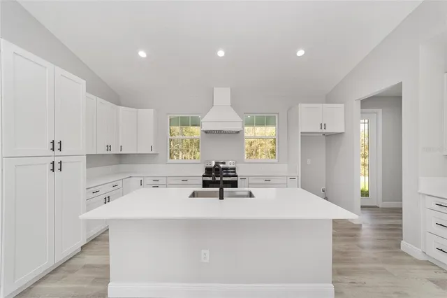 a view of a kitchen with kitchen island a sink stainless steel appliances and cabinets