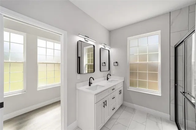 a bathroom with a double vanity sink bathtub and next to a window