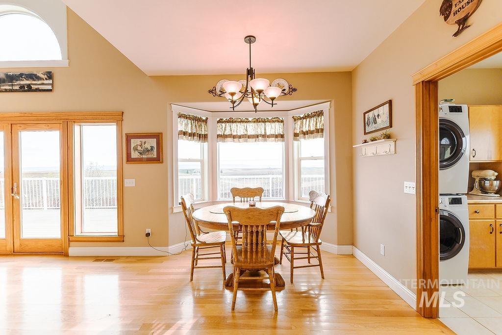 18072 Central Grd Genesee, ID 83832 - Photo 17 of 50 Dining room with light wood-style floors, stacked washing machine and dryer, and a chandelier