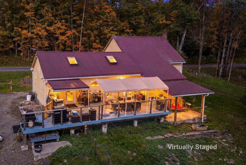 1668 Vandervort Hill Road Unadilla, NY 13849 - Photo 40 of 50 An elevated wood deck with covered dining spaces overlooks the surrounding forest landscape.