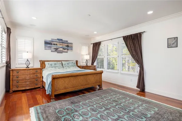 a spacious bedroom with a bed and wooden floor