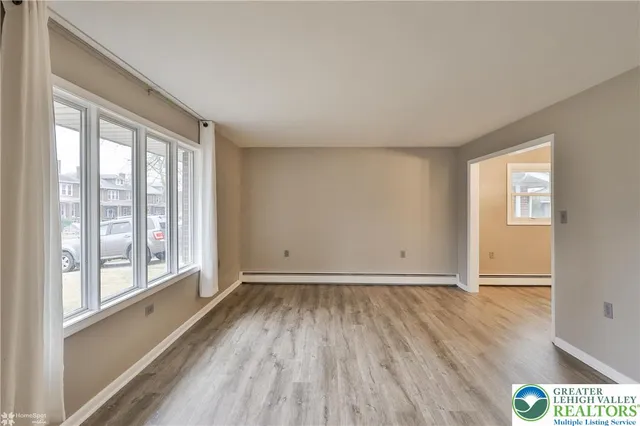 a view of an empty room with wooden floor and a window