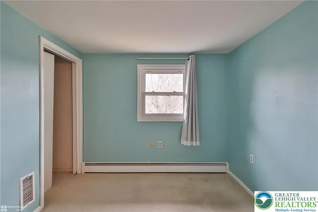 a view of an empty room with windows and closet