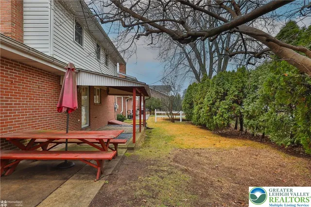 a backyard of a house with table and chairs under an umbrella