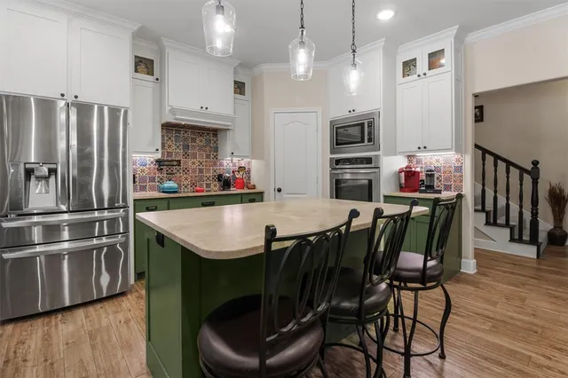 a kitchen with stainless steel appliances granite countertop a kitchen island hardwood floor and a refrigerator