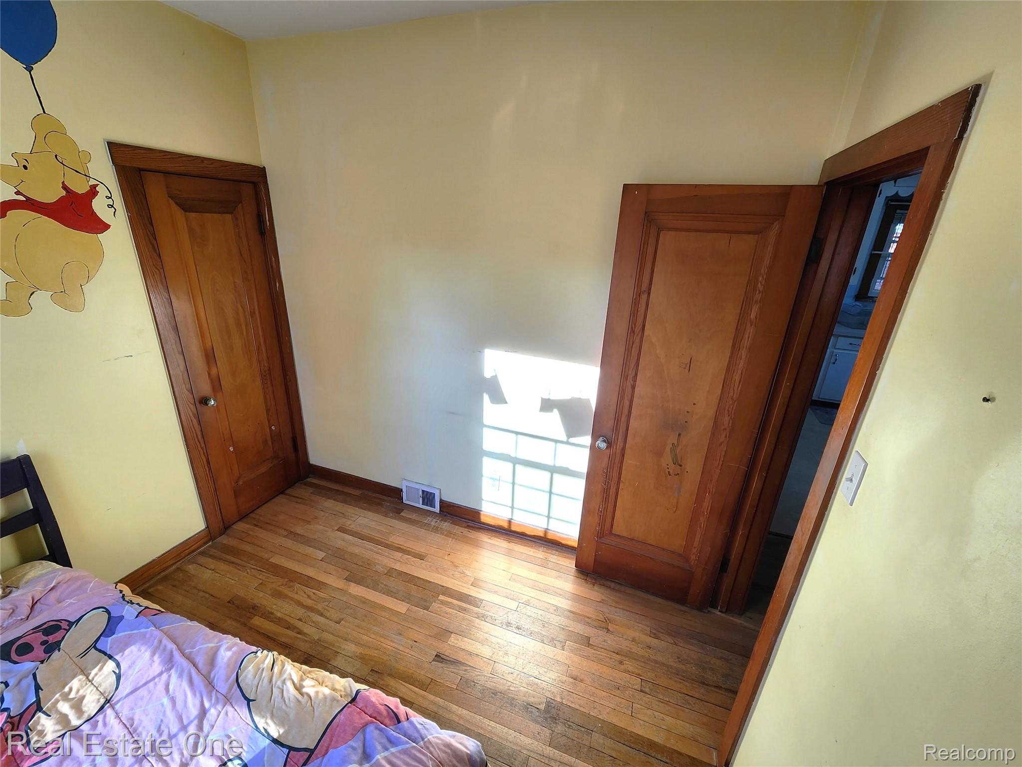 2153 Wiltshire Road Berkley, MI 48072 - Photo 15 of 18 Room featuring wood-finish flooring, two paneled wood doors, and a floor vent