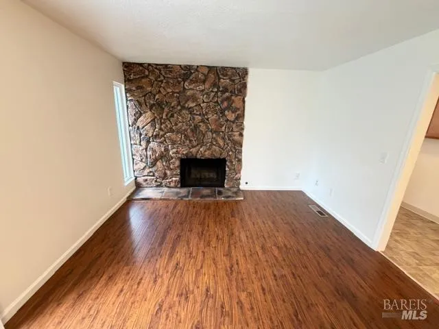 a view of empty room with wooden floor and fireplace