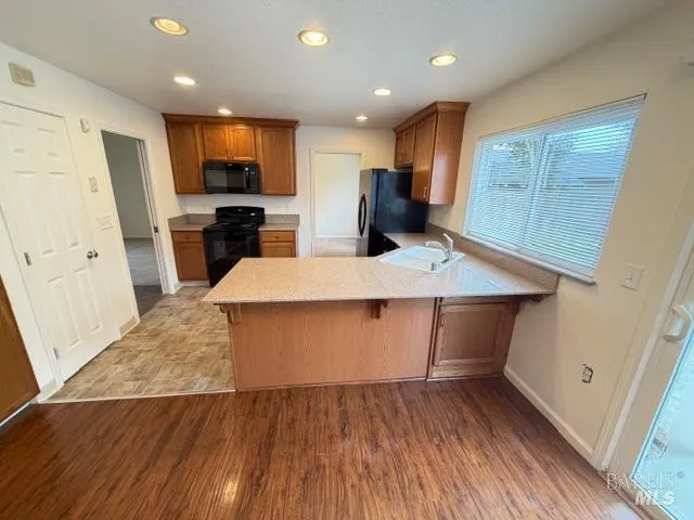 a large kitchen with stainless steel appliances kitchen island a large counter top and wooden floors