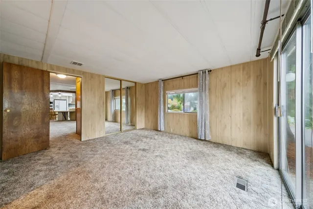 a bedroom with a bed a table and large window