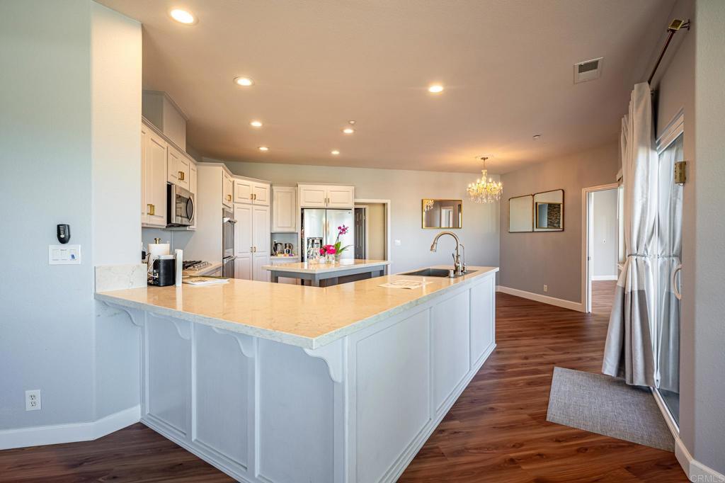 30606 Falling Star Circle Valley Center, CA 92082 - Photo 39 of 70 a large white kitchen with stainless steel appliances granite countertop a lot of counter space and wooden floors