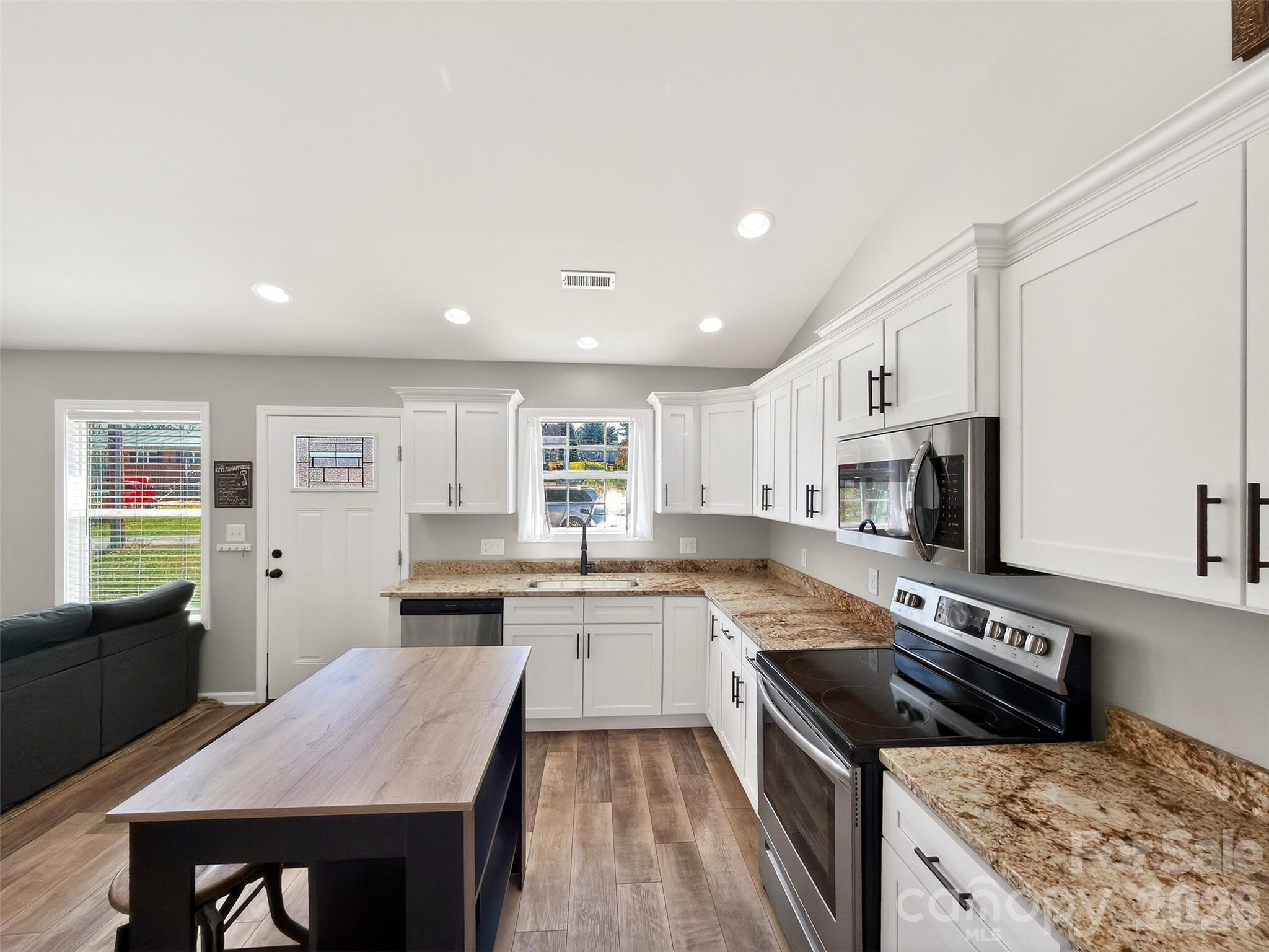 116 Bostic Street Marion, NC 28752 - Photo 7 of 28 a kitchen with stainless steel appliances granite countertop a stove top oven a sink dishwasher and a refrigerator with wooden floor