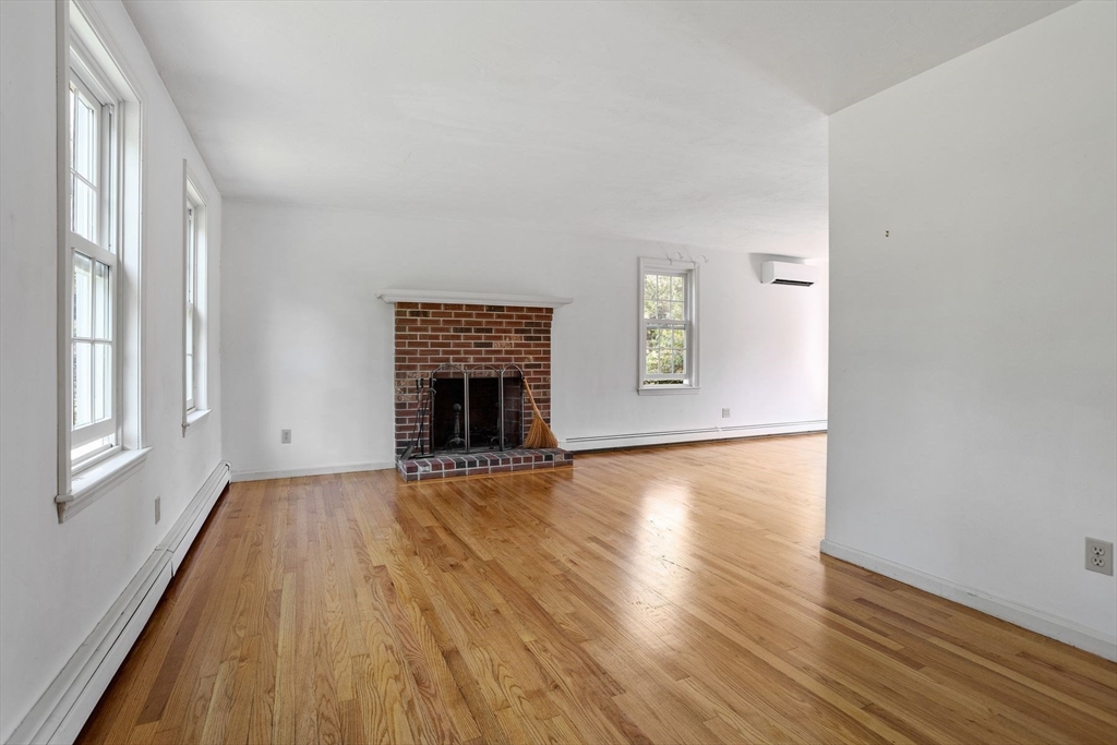 10 Farm Road Stow, MA 01775 - Photo 8 of 37 an empty room with wooden floor a fireplace and windows