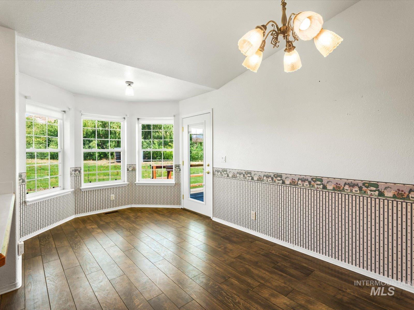 3540 Wills Road Emmett, ID 83617 - Photo 10 of 36 Dining area featuring wood-finish flooring, a bay window with three double-hung windows, a vaulted ceiling, and a chandelier