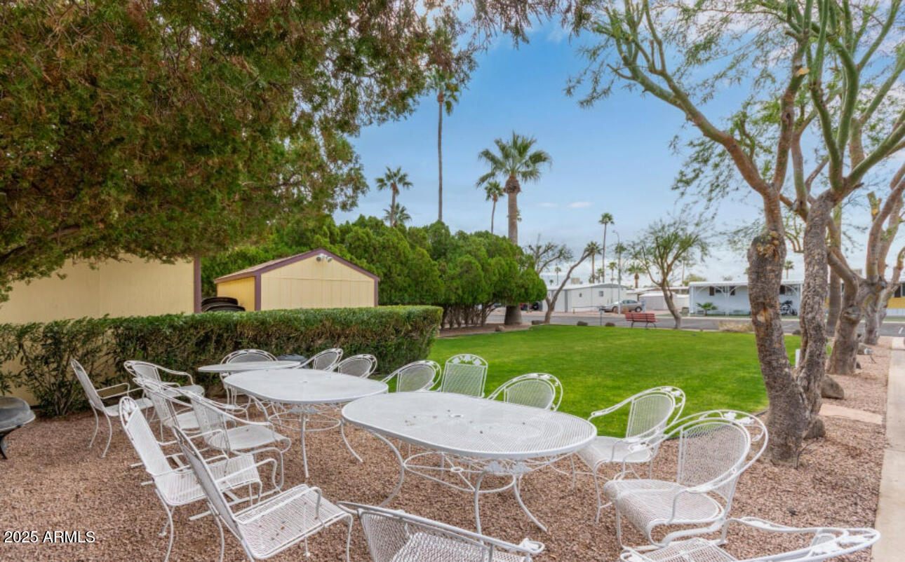 11425 East University Drive, Unit 120 Apache Junction, AZ 85120 - Photo 36 of 43 a view of a patio with table and chairs potted plants and a large tree