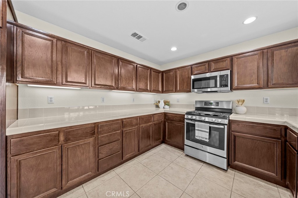 11344 Magnolia Street Corona, CA 92883 - Photo 22 of 75 a kitchen with stainless steel appliances granite countertop a stove top oven a sink dishwasher and a refrigerator