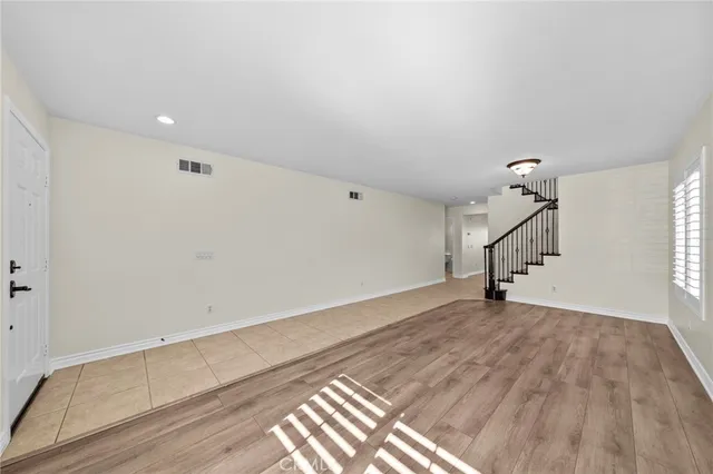 a view of an empty room with wooden floor and stairs