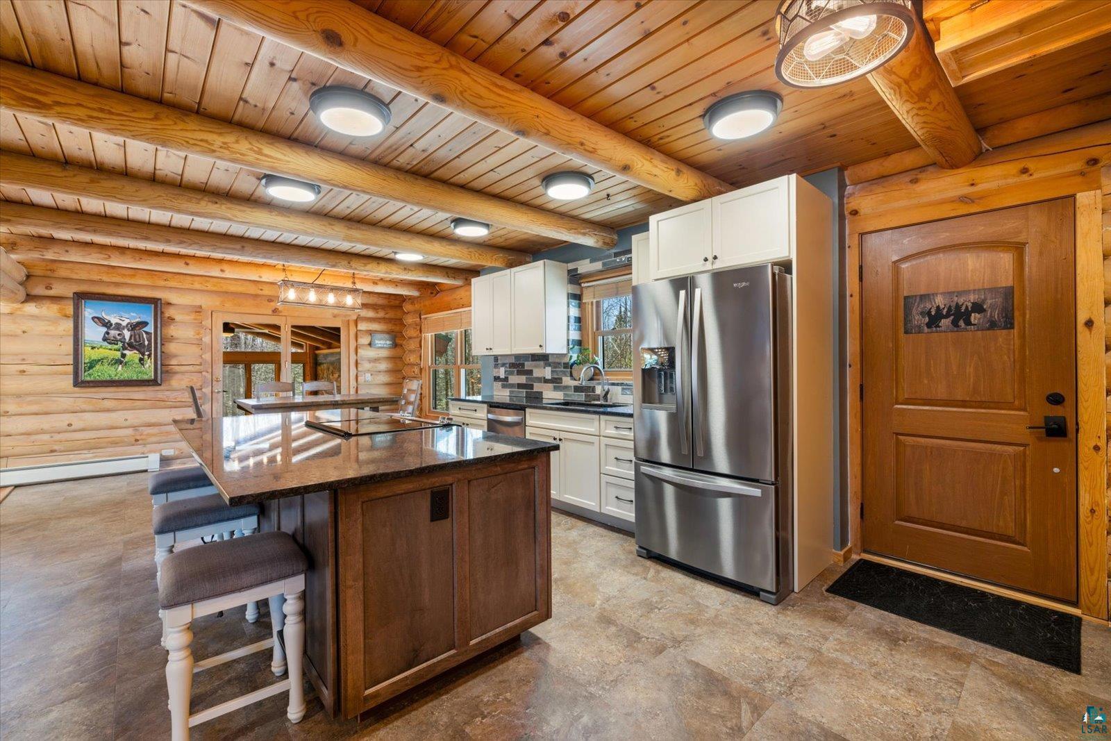 717 Bourgin Road Virginia, MN 55792 - Photo 12 of 47 Kitchen with stainless steel appliances, log walls, wooden ceiling, a kitchen breakfast bar, and white cabinetry