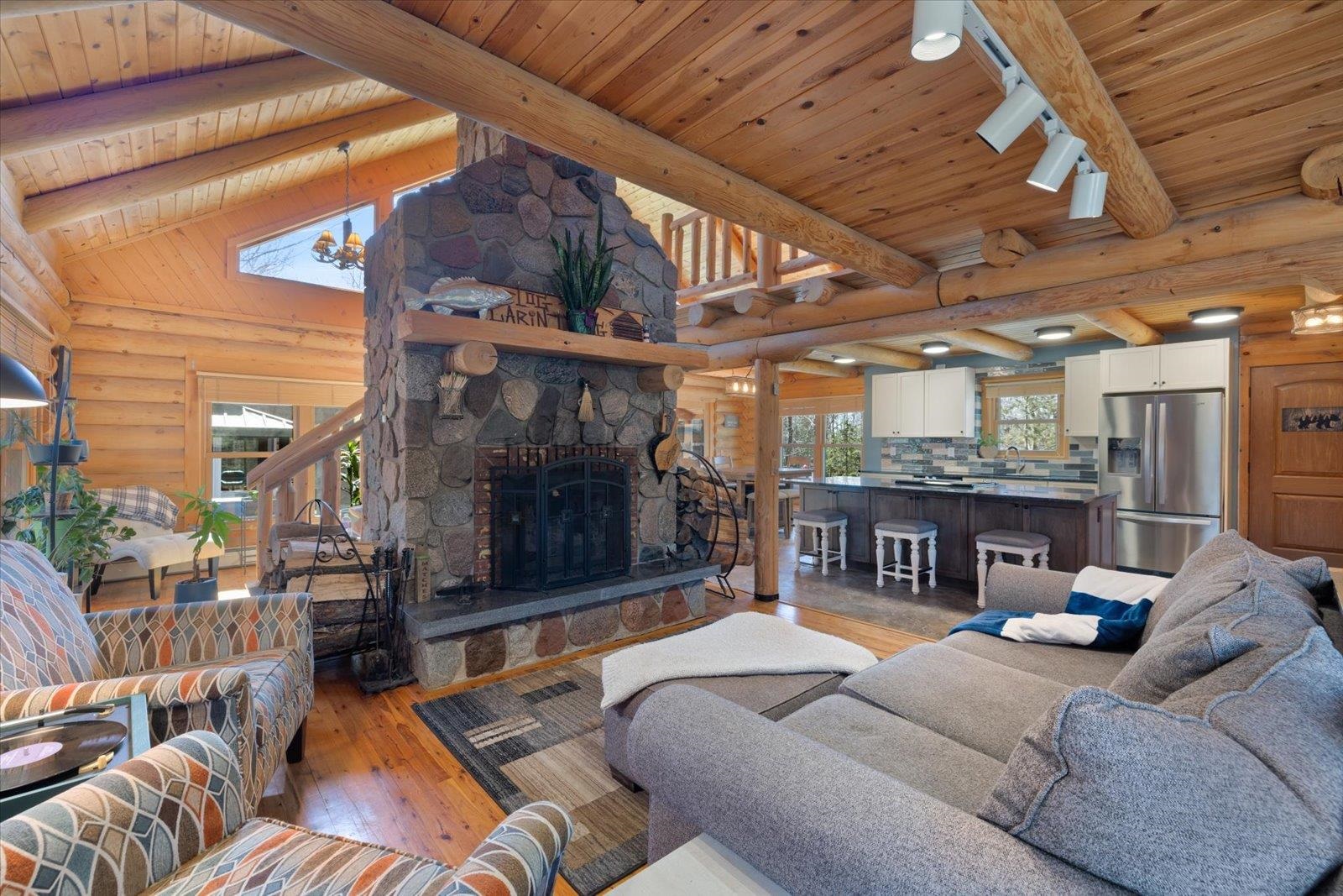 717 Bourgin Road Virginia, MN 55792 - Photo 3 of 47 Living room with light wood-type flooring, wood ceiling, rustic walls, and a stone fireplace