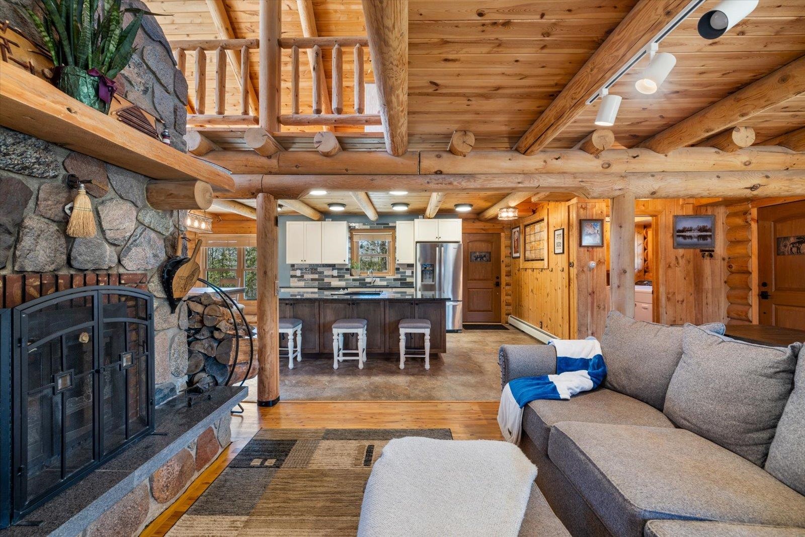 717 Bourgin Road Virginia, MN 55792 - Photo 4 of 47 Living area featuring light wood-style flooring, a fireplace, wood ceiling, log walls, and beamed ceiling