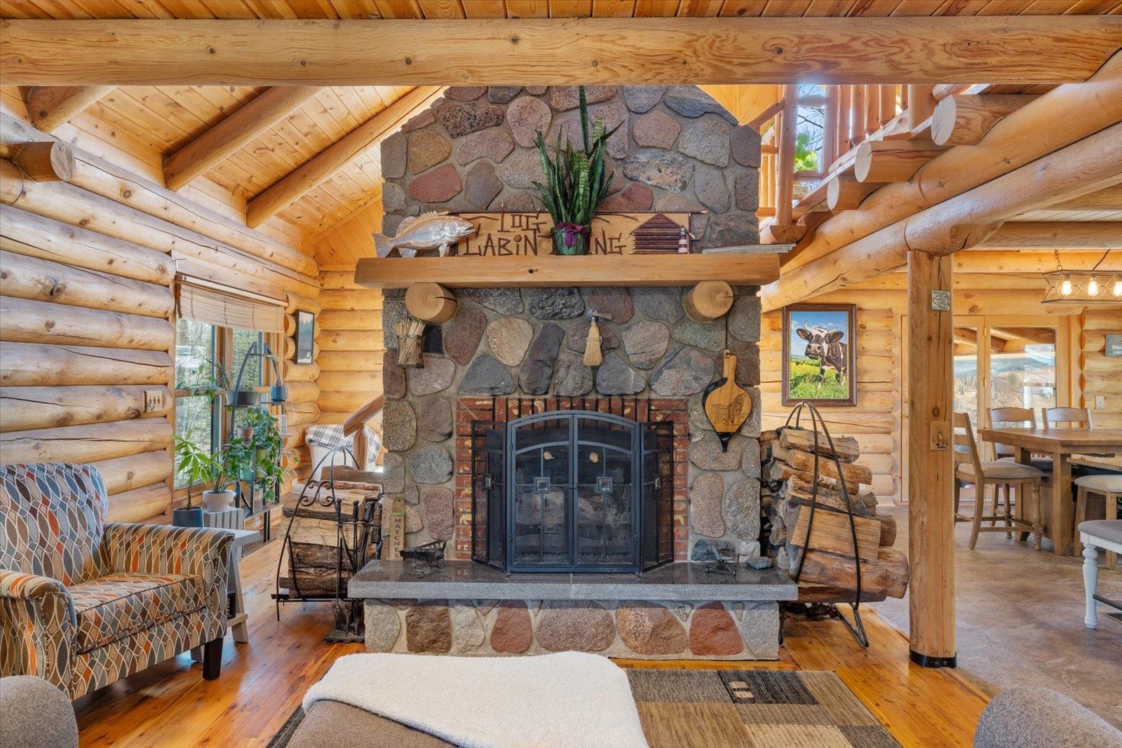 717 Bourgin Road Virginia, MN 55792 - Photo 5 of 47 Living area featuring wooden ceiling, beam ceiling, rustic walls, plenty of natural light, and a stone fireplace