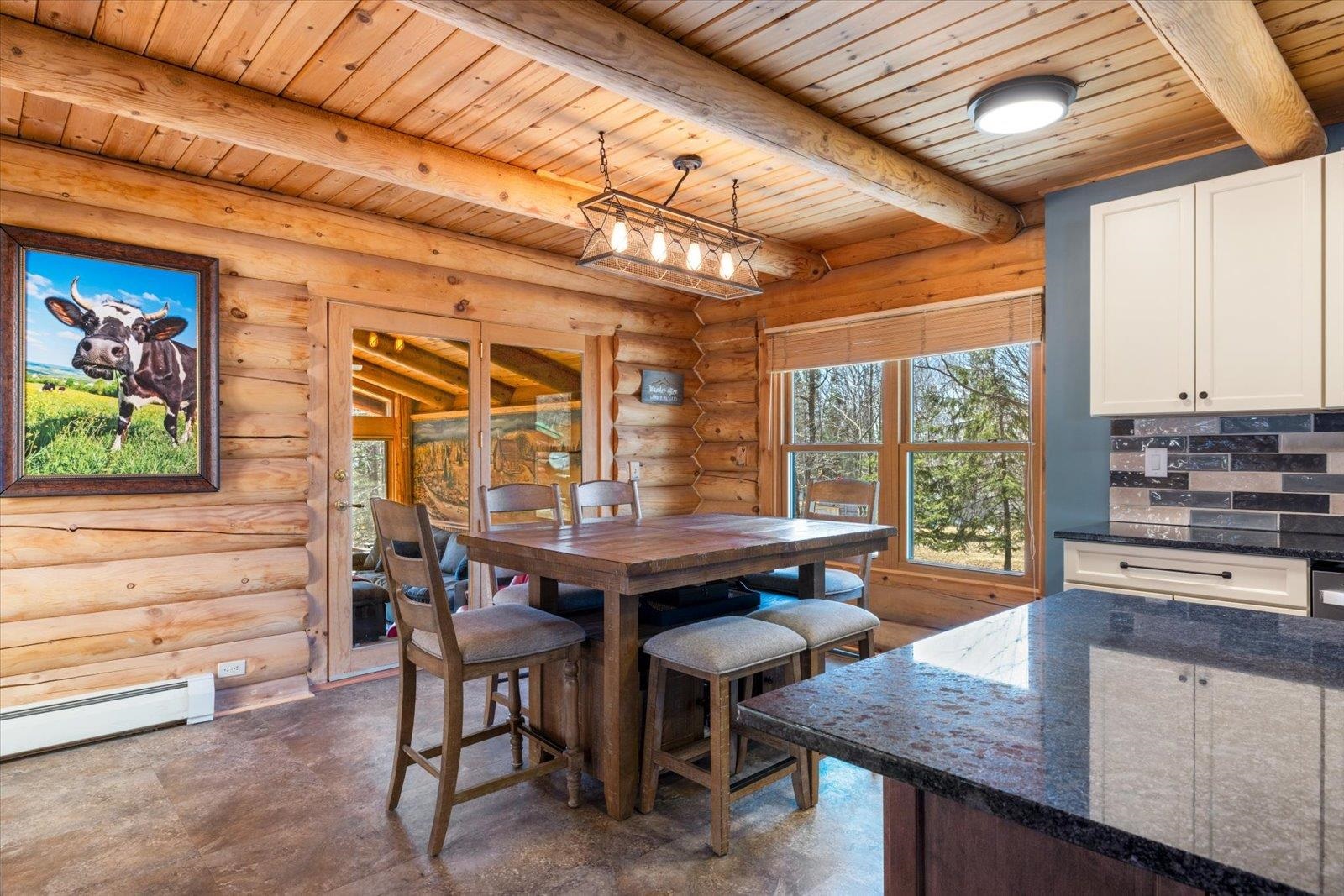 717 Bourgin Road Virginia, MN 55792 - Photo 6 of 47 Dining area featuring wooden ceiling, concrete floors, log walls, a baseboard radiator, and beamed ceiling