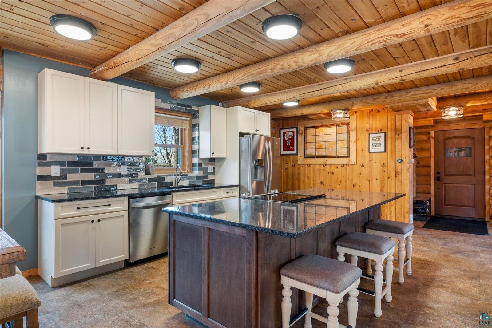 717 Bourgin Road Virginia, MN 55792 - Photo 10 of 47 Kitchen with appliances with stainless steel finishes, a sink, wood ceiling, a kitchen breakfast bar, and tasteful backsplash