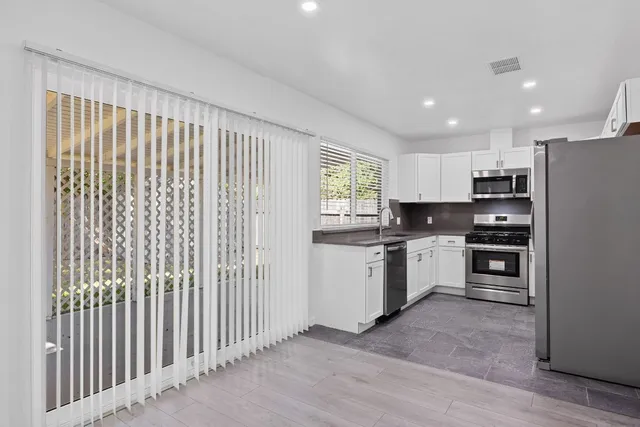 a kitchen with white cabinets and appliances