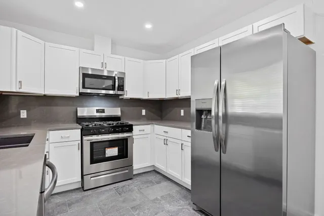 a kitchen with stainless steel appliances a refrigerator sink and white cabinets