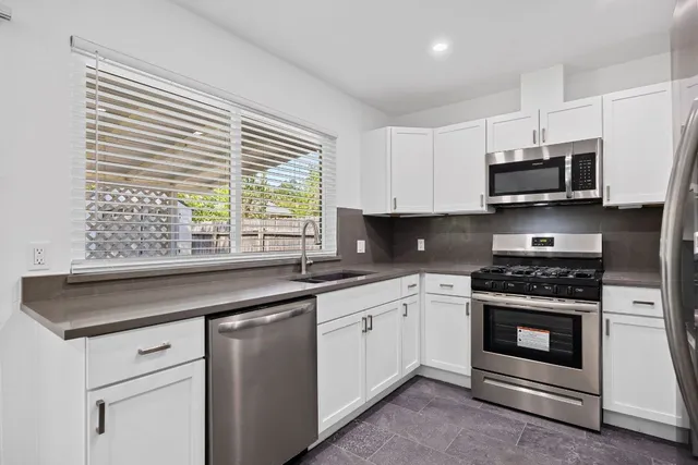 a kitchen with stainless steel appliances granite countertop a sink a stove and cabinets