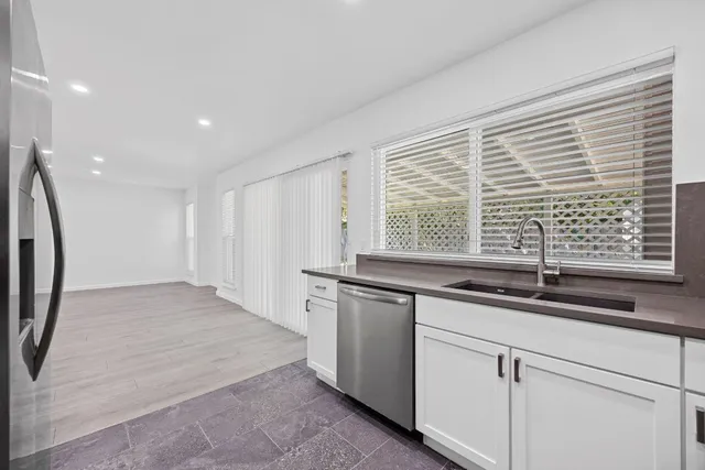 a kitchen with granite countertop a sink and a white wooden cabinets