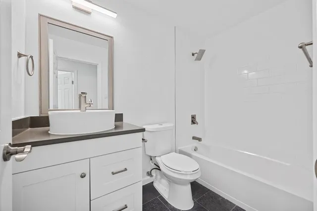 a bathroom with a toilet a sink a mirror and vanity