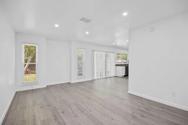 an empty room with wooden floor and windows