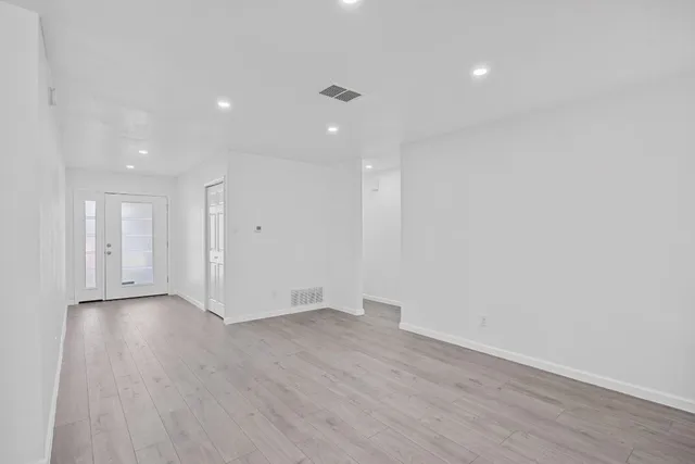 an empty room with wooden floor and windows