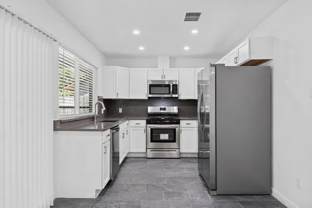 a kitchen with stainless steel appliances granite countertop a refrigerator and a stove top oven