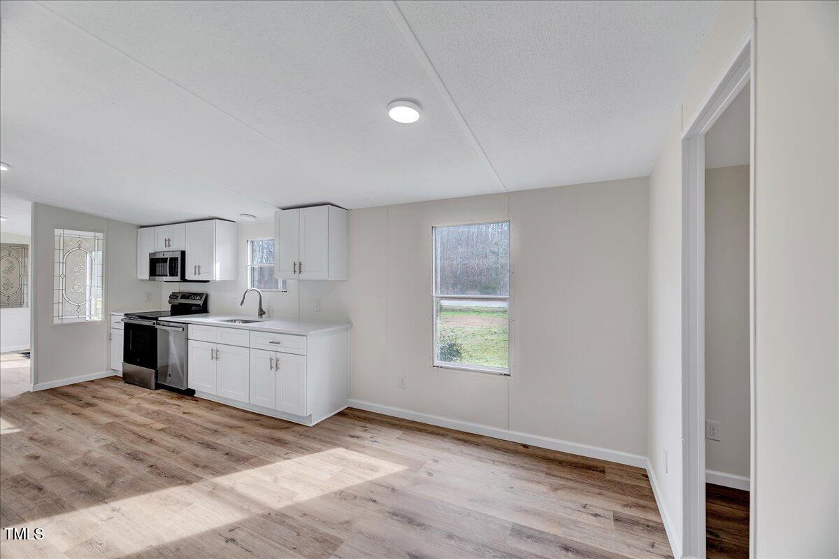 10942 Simms Road Bailey, NC 27807 - Photo 23 of 44 a large white kitchen with kitchen island a sink stainless steel appliances and cabinets