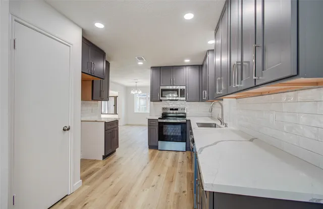 a large kitchen with stainless steel appliances granite countertop a refrigerator a sink dishwasher a stove and a microwave oven on the granite countertops