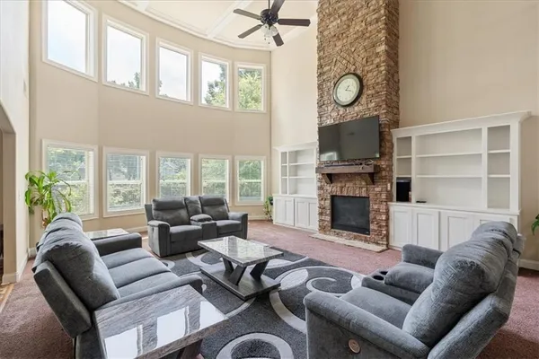 a living room with furniture a fireplace a flat screen tv and a large window