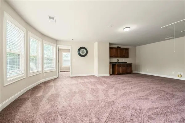 a view of empty room with a windows and kitchen view