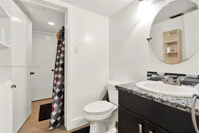 a bathroom with a granite countertop toilet sink and mirror