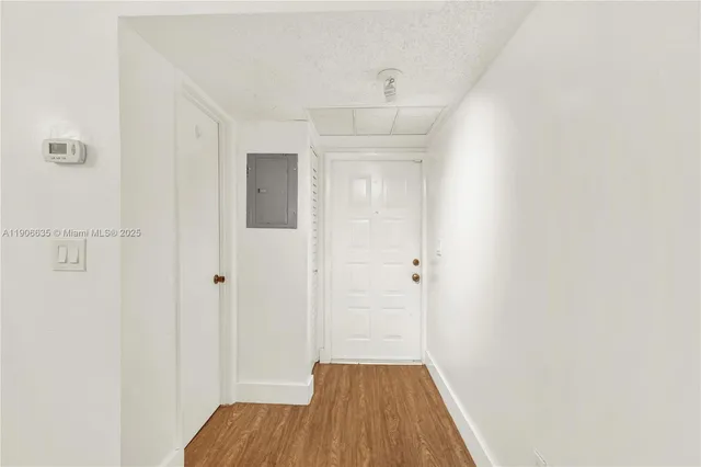 a view of a hallway with wooden floor and a bathroom